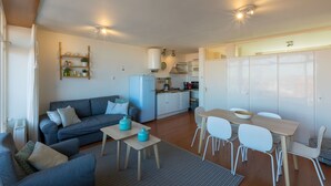 A compact living space with a sofa, dining table, chairs, a kitchen area, and a built-in wardrobe. - Romantic Coastal Retreat With Scenic Balcony (Zoutelande)