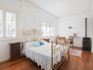 A bedroom with a bed, bedside table, chair, and a fireplace.