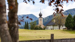 A church with a bell tower in a rural setting with mountains in the background. - Apartment in Hohentauern Near Ski Lift (Hohentauern)