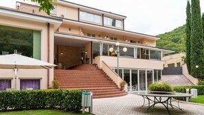 Ein modernes, zweistöckiges Haus mit einer Treppe, die zu der oberen Etage führt, einer überdachten Außenlounge und einem gepflegten Garten.