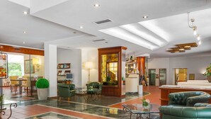 Eine großzügige Lobby mit Marmorboden, Ledersitzmöbeln, einer Rezeption und einem großen Fenster mit Blick ins Freie.