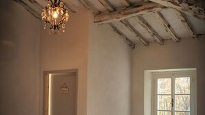 A room with a chandelier, a door labeled "Bathroom," and a window with a view of trees. - Belvilla by OYO Villa Pian di Fiore (Pratovecchio Stia)