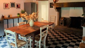 A dining area with a wooden table and chairs, a vase with dried flowers, a checkered floor, and a fireplace. - Belvilla by OYO Villa Pian di Fiore (Pratovecchio Stia)