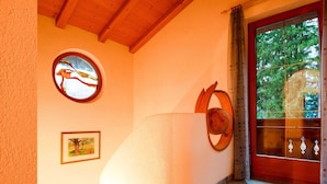 Un couloir doté d’un plafond en bois, d’une rosace vitrail et d’une porte à cadre rouge.