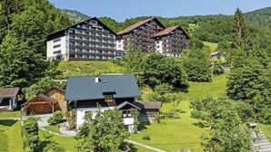 Eine Berglodge mit mehreren Gebäuden, darunter ein großes Hotel mit Balkonen und kleinere Holzhütten.