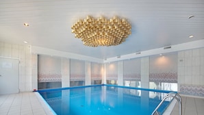 Ein Swimmingpool mit blauer Innenauskleidung, umgeben von gefliesten Wänden und einem gemusterten Mosaik.