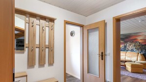 A room with a wooden wardrobe, a small desk, and a door leading to another room with a leopard painting. - Ruhige Gartenwohnung in Dresden (Dresden)