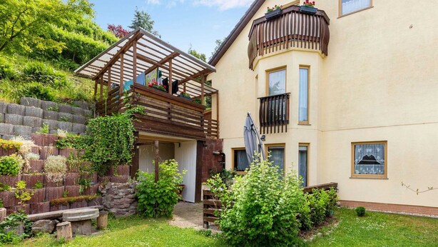 A two-story building with a wooden deck and a balcony. - Ruhige Gartenwohnung in Dresden (Dresden)