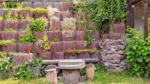 A garden with a tiered brick wall, wooden table, and stone steps. - Ruhige Gartenwohnung in Dresden (Dresden)