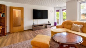 A living room with a wooden ceiling, a flat-screen TV, a sofa, and a coffee table. - Ruhige Gartenwohnung in Dresden (Dresden)