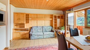 A cozy room with a wooden ceiling, a sofa, a dining table, and a view of the outdoors. - Peaceful Apartment in Fügenberg near Ski Area (Fuegenberg)