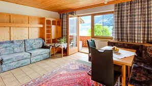 A cozy room with a wooden ceiling, a sofa, a dining table with chairs, and a view of the outdoors through a large window. - Peaceful Apartment in Fügenberg near Ski Area (Fuegenberg)