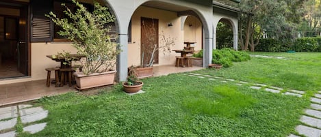 A house with a covered patio, outdoor seating, and a well-maintained lawn.