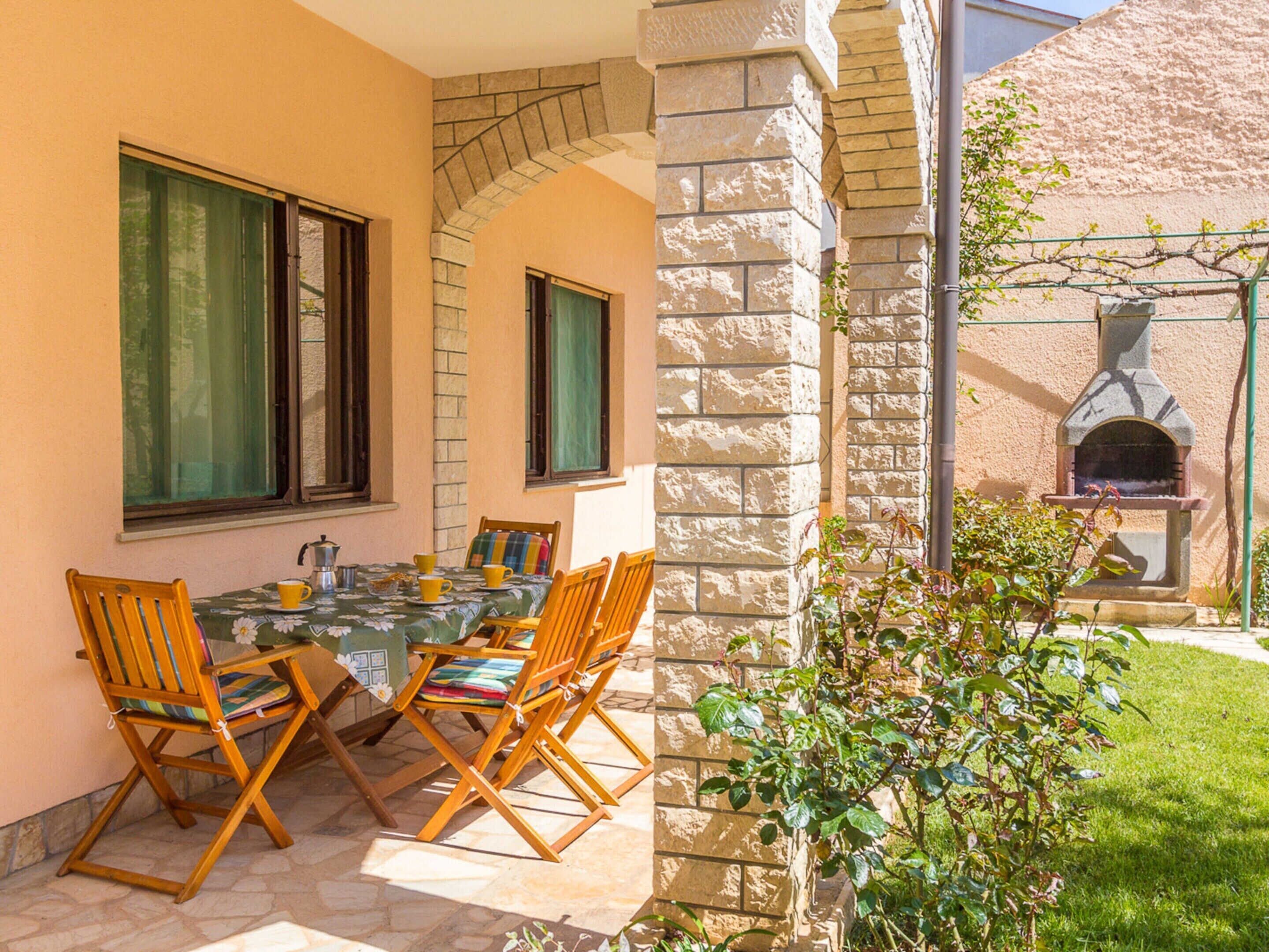 An outdoor patio with a table and chairs, a stone wall, and a brick oven.