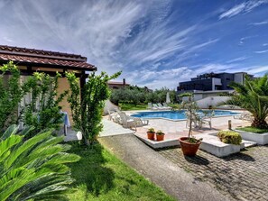 Un espace piscine comprenant des chaises longues, une petite piscine et des plantes en pot.