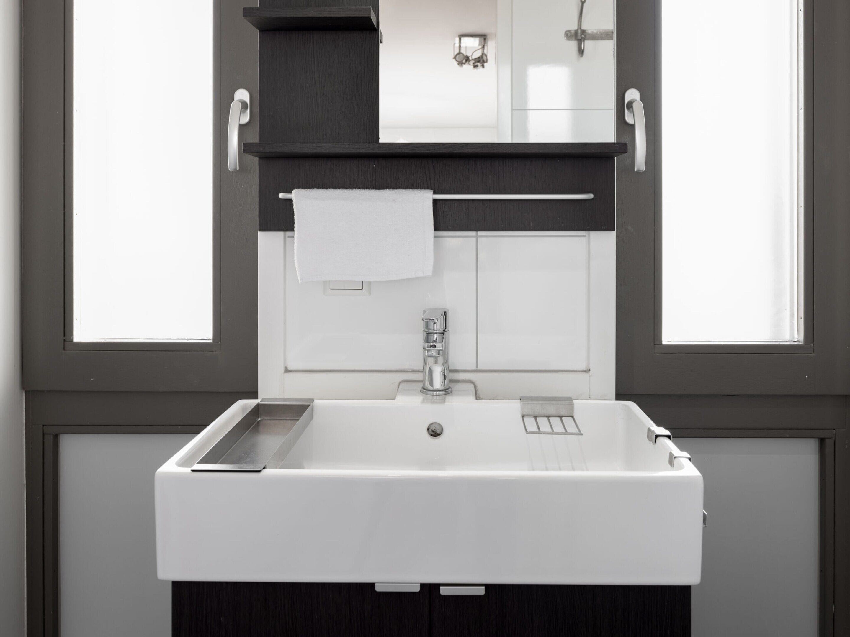 A bathroom with a white sink, a towel hanging on a rack, and a mirror above the sink.