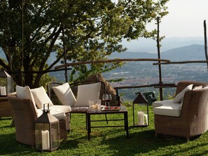 A cozy outdoor seating area with wicker furniture and candles, overlooking a scenic landscape. - Villa in Tuscany With Organic Wine Estate (Arezzo)