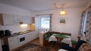 Et lille køkken med spiseplads, en sofa og et bord med grønt dug.
