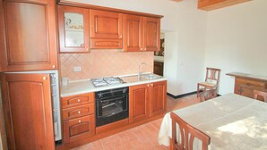 A kitchen with wooden cabinets, a stove, and a sink. - Belvilla by OYO Tuscan Farmhouse With Private Pool (Montescudaio)