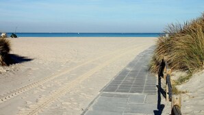 A sandy beach with a paved walkway leading to the sea, surrounded by dunes. - Belvilla by OYO Tuscan Farmhouse With Private Pool (Montescudaio)