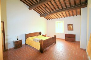 A bedroom with a wooden bed, a nightstand, a dresser, and a window with natural light.