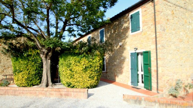 A stone building with a gravel driveway, green shutters, and a tree in front. - Belvilla by OYO Tuscan Farmhouse With Private Pool (Montescudaio)