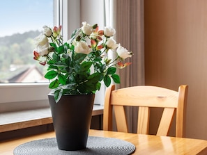 A potted plant with white flowers on a table by a window.