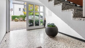 A modern interior with a terrazzo floor, a large potted plant, and a view through a glass door to an outdoor seating area. - Plush Apartment in Bollendorf with Sauna near Luxembourg (Bollendorf)