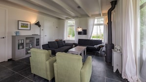 Ett vardagsrum med en öppen spis, två soffor, ett soffbord och ett skåp.