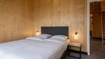 Una habitación con paneles de madera, una cama, dos lámparas de noche y una mesita.