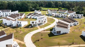 A modern residential complex with white buildings, green lawns, and a curved driveway.