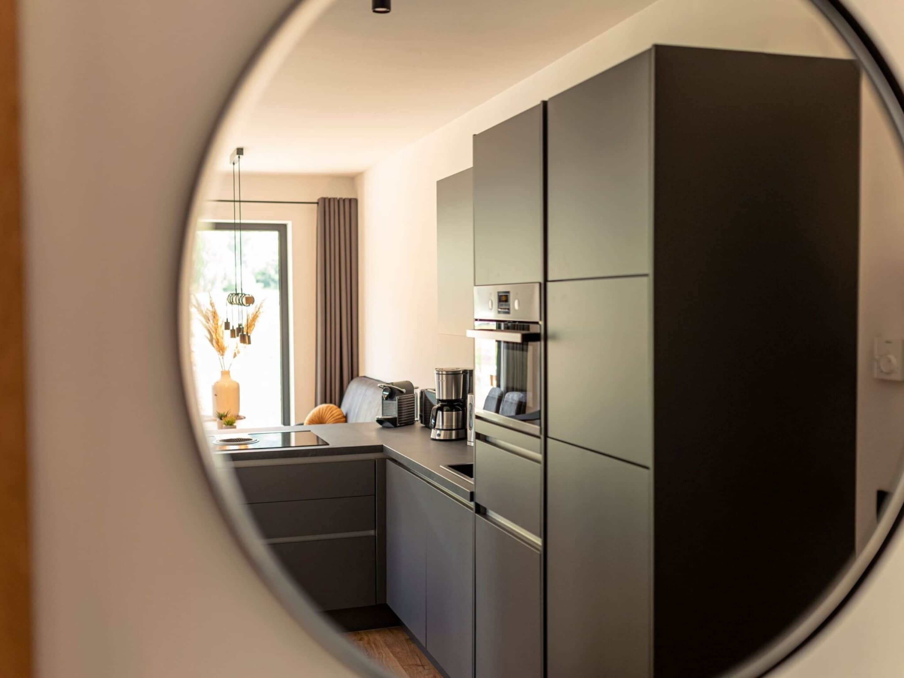 A modern kitchen with dark cabinetry, a coffee machine, and a window with curtains.