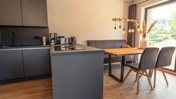 A modern kitchen with a central island, dark cabinets, and a dining area with a wooden table and chairs.