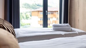 A hotel room with a bed, a window with curtains, and a view of a building in the background. - Luxurious Apartment in St Georgen am Kreischberg With Sauna (Sankt Georgen am Kreischberg)