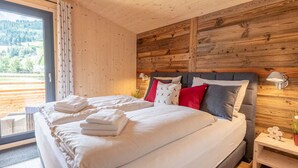 A bedroom with a large bed, wooden walls, a window with curtains, and a nightstand with a lamp. - Apartment With Infrared Sauna (Sankt Georgen am Kreischberg)