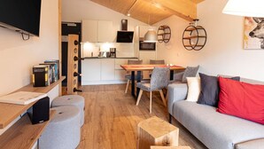 A modern living room with a grey sofa, wooden coffee table, and a dining area with a table and chairs. - Apartment With Infrared Sauna (Sankt Georgen am Kreischberg)