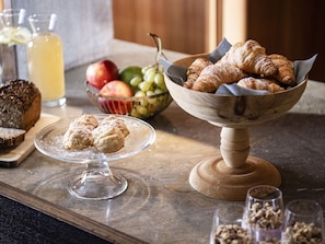 A breakfast setting with pastries, a bowl of fruits, and a loaf of bread on a marble countertop. - Apartment in Dolomites With Wellness Area (Castelrotto)