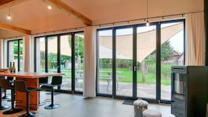 A spacious room with a large sliding glass door leading to a patio, a wooden table with chairs, and a black refrigerator.