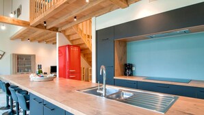 A modern kitchen with a wooden countertop, a red refrigerator, and a built-in sink.