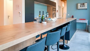 A modern kitchen with a long island counter, bar stools, and a built-in oven.