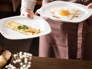 A person holding two plates, one with an omelette and the other with a fried egg. - Pet-friendly Mountain Escape (Castelrotto)