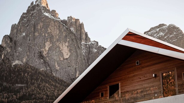 A mountain cabin with a sloped roof, wooden exterior, and a view of a rugged mountain range. - Flat in Alpe di Siusi With Wellness Area (Castelrotto)