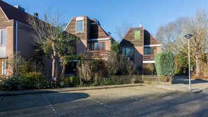 Un immeuble résidentiel à la façade en briques, doté de nombreuses fenêtres et d’une allée pavée.