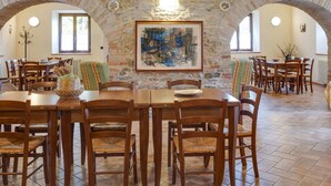 A dining area with a stone wall, wooden tables, and chairs. - Belvilla by OYO Aiolina (Sant'Angelo in Vado)