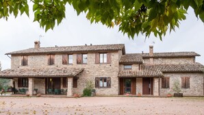 A stone building with a covered patio and a gravel driveway. - Belvilla by OYO Aiolina (Sant'Angelo in Vado)
