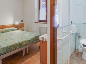 Ein kleines, sauberes Zimmer mit einem Bett, einem Heizkörper, einer Dusche und einem WC.