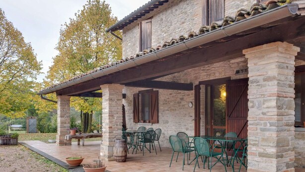 A stone building with a covered patio area, outdoor seating, and a rustic aesthetic. - Belvilla by OYO Aiolina (Sant'Angelo in Vado)