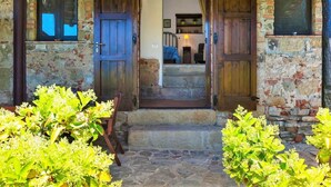 A rustic stone building with wooden doors and a staircase leading to an upper level. - Villa in Velia Near Roman Ruins and Beach (Ascea)