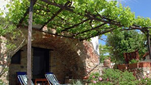 A stone building with a pergola, two lounge chairs, and potted plants. - Villa in Velia Near Roman Ruins and Beach (Ascea)