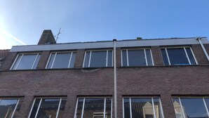 A multi-story building with a flat roof and large windows.